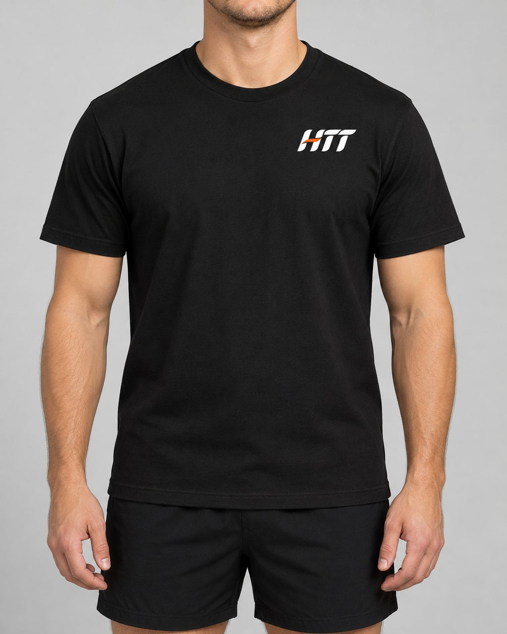 Front of a black HTT standard fit tee on a model, small HTT logo on the left chest. Fitted on the arms, not tight.